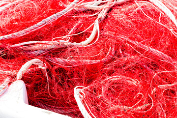 Filet de pêche en nylon rouge rangé en tas dans un bac au retour de la pêche en mer.