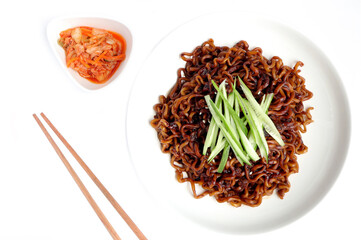Jajangmyeon instant noodles with black bean sauce on white plate.Homemade dried Korean black sauce instant noodles decorated with cucumber served with kimchi.