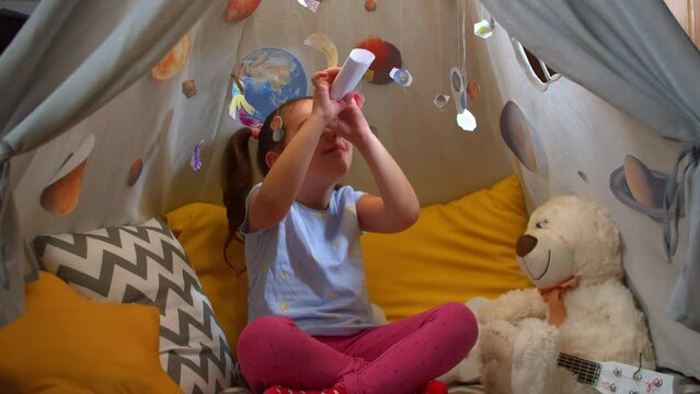 Cute preschool girl is exploring planets and space by playing games at home.