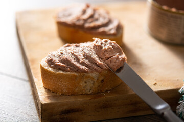 Dipping toasted bread with pork liver pate on wooden table