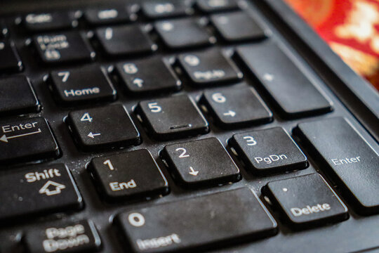 Closeup shot of an old dusty laptop keyboard, worn-out keys of numeric digits on computer