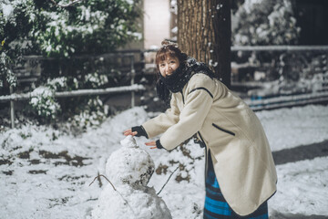 公園で雪だるまを作る女性