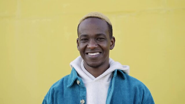 African American Positive Young Man looking to the camera, smiling over yellow background. Portrait Human Expression