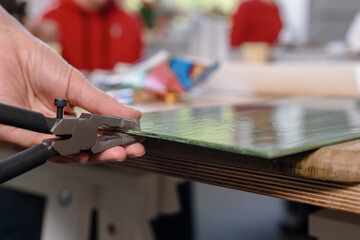 Closeup of artist cutting sheet of green glass into small mosaic pieces