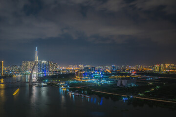 Fototapeta na wymiar Aerial view of Bitexco Tower, buildings, roads, Thu Thiem 2 bridge and Saigon river in Ho Chi Minh city - Far away is Landmark 81 skyscrapper. This city is a popular tourist destination of Vietnam