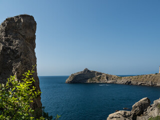 Seascape. View from behind the rocks to the blue sea. Summer. Sunlight, blue sky. World travel concept. Beautiful rock masses along the seashore.