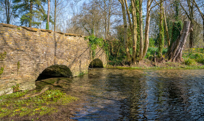 Fototapeta na wymiar Stone bridge over the River Leach in the Cotswold village of Southrop, Gloucestershire, United Kingdom