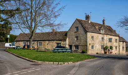 Fototapeta na wymiar The Village Green and the Swan public house in Southrop, the Cotswolds, England, United Kingdom