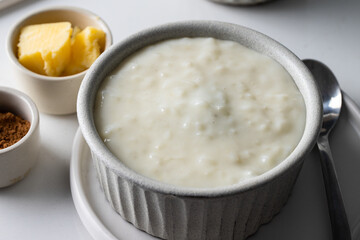 Rice pudding in grey ceramic bowl on white table. Breakfast