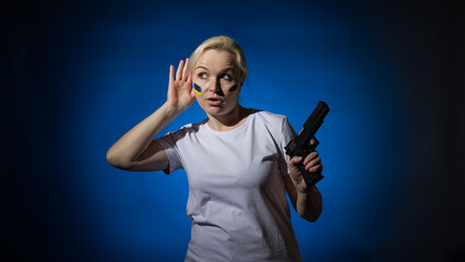 A woman with a gun and a blue and yellow Ukrainian flag on her cheek eavesdrops. Dark background.