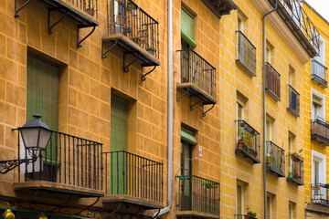 Fototapeta na wymiar Row of buildings with different varieties of yellow in the alleys of the barrio de la latina in Madrid, Spain.