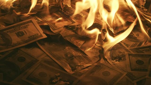Bunch of dollar bills slowly burn up in closeup Macro. Concept of a big waste of money