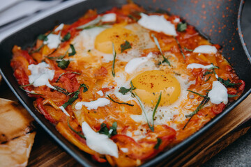 Closeup of two fried eggs and vegetables in a frying pan. Shakshouka eggs with tomatoes.