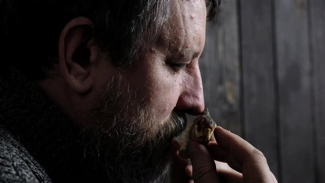 bearded adult caucasian man sniffing a dry dried fish vobla