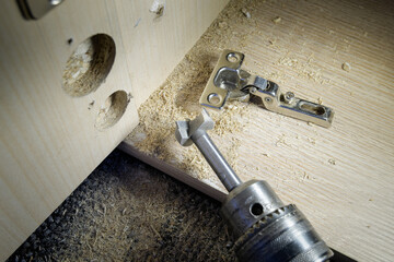 Hinge fixed on a modern cabinet. Tools for installation furniture fittings.