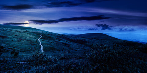 carpathian mountain landscape in summer at night. dirt road and hiking trail track. panoramic view of a hilly countryside in full moon light. fairy tale spooky looking abstract picture