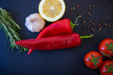Red vegetables on a black background. Peppers and tomatoes, garlic