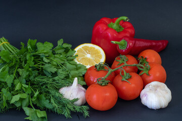 Red vegetables on a black background. Peppers and tomatoes, garlic