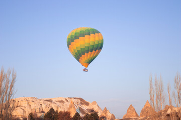 Fototapeta na wymiar A bright green hot air balloon flying over the mountains landscape