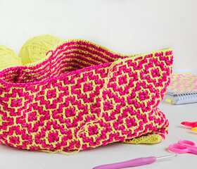 The process of creating a crochet bag with bright pink yellow rhombus. Modern crochet fabric with mosaic technique. Art handmade concept.