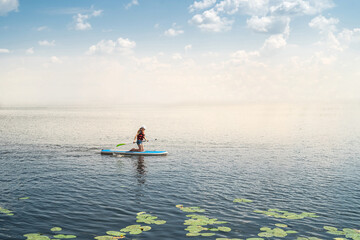 Fototapeta na wymiar Young woman relax on SUP Stand up paddle board in summer time