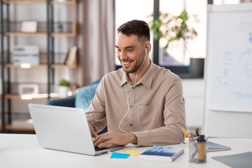 Fototapeta premium distant education, school and remote job concept - happy smiling male teacher with laptop computer and wireless earphones working at home office