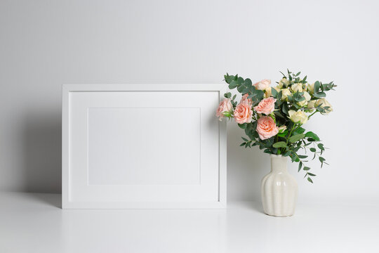 Landscape wooden frame mockup for artwork, photo and painting presentation. White interior walll with roses flowers bouquet.