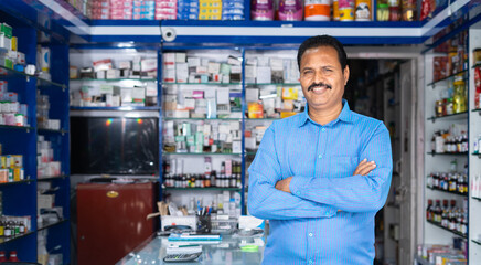 Portrait shot of Happy medical shop owner standing with crossed arms by looking at camera at...