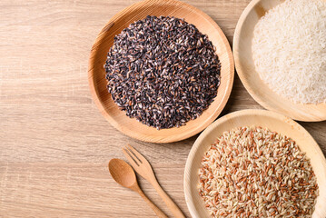 Various Organic Thai rice grain (brown, purple and white rice) on wooden background, Table top view