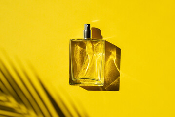 Transparent bottle of perfume with label on a yellow background. Fragrance presentation with...