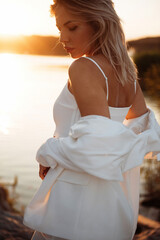 Gorgeous blonde in suit standing near lake during sunset