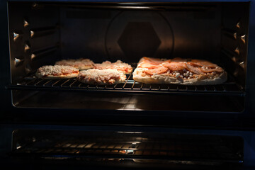 Frozen pizza semi-finished product with tomato sause and cheese on grill prepared for baking in oven. Selective focus