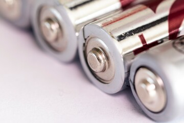 A macro portrait of the plus or positive side of a couple of triple A or AAA batteries lying on an...
