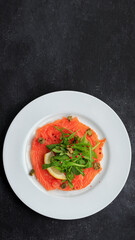 Salmon carpaccio, on a plate, with lemon , on concrete