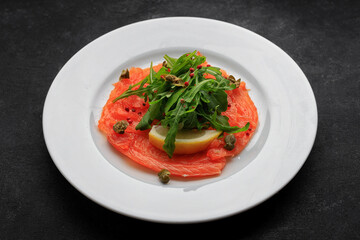 Salmon carpaccio, on a plate, with lemon , on concrete
