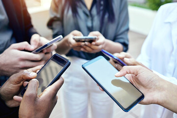 It is amazing what you can accomplish together. Shot of a group of unrecognisable businesspeople using their cellphones together at and outside meeting.