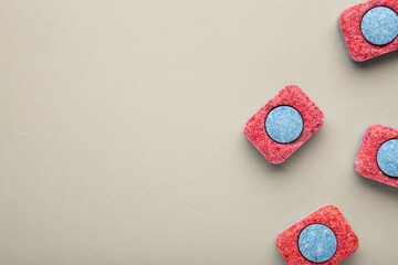 Red and blue tablets for dishwashing machine. Detergents for home hygiene. Dishwasher capsules on grey background.