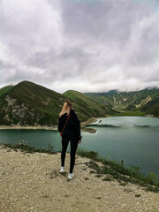 Fototapeta na wymiar A girl on the background of Lake Kezenoy-am in the Caucasus mountains in Chechnya, Russia June 2021.
