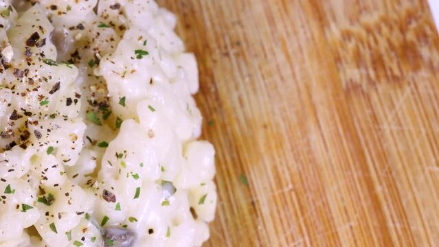 Macro shot of risotto dish on wood surface. Close view from above in 4k, rotation motion.