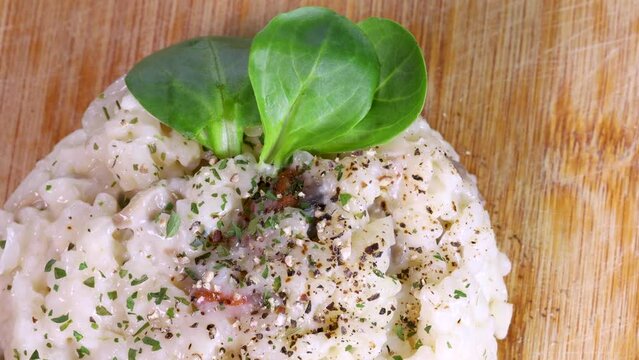 Risotto dish on wood surface, macro shot in 4k. Close view from above, rotation motion.