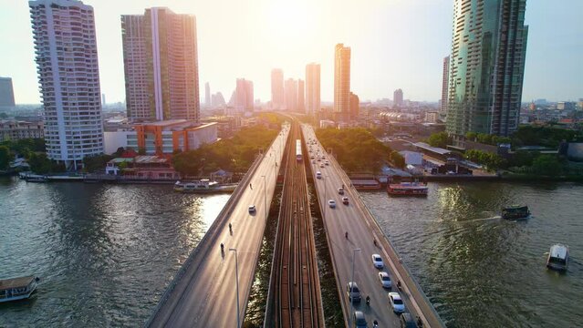 Aerial view flight over a moving sky train on a bridge over the Chao Phraya River, Bangkok, Thailand. Drone 4K shot.
