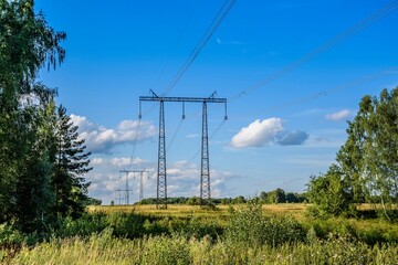 Electric power transmission line on steel supports and a beautiful landscape in the early summer evening. Power lines.