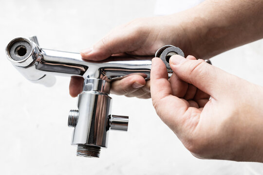 plumber installs paronite gasket in shower faucet closeup and gray concrete board in background