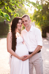Obraz premium Happy and young pregnant couple in park in summer
