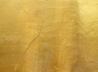 Gold plastered concrete wall with cracks, background
