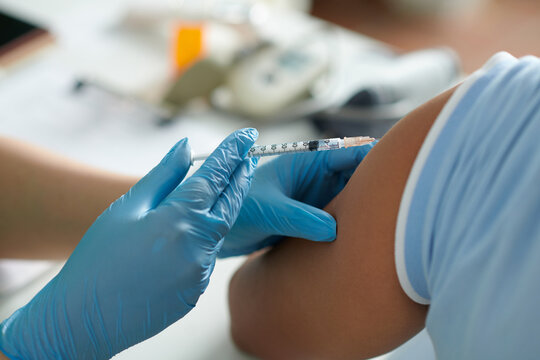 Closeup image of medical nurse injecting vaccine against virus in shoulder of patient
