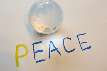 ガラスの地球儀と平和の標語　反戦イメージ　glass globe and text of "PEACE"	