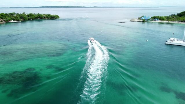 Aerial shot of boat moving slowly in blue water ocean in Rosario Islands, Cartagena, Colombia
