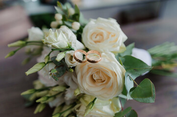 Golden wedding rings on the bride's bouquet of white flowers