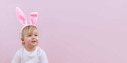 Obraz na płótnie Canvas A cute little baby with rabbit ears on a pink background.